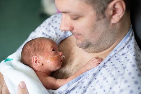 Man holding baby on chest