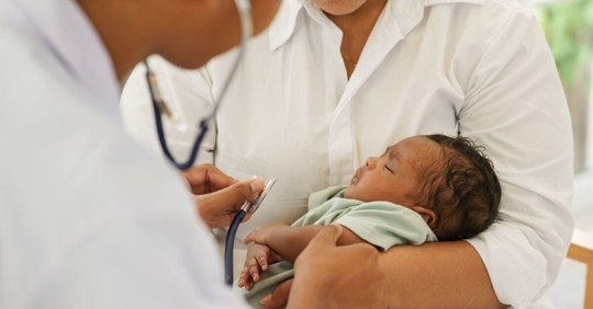 Doctor examining newborn with a stethoscope.