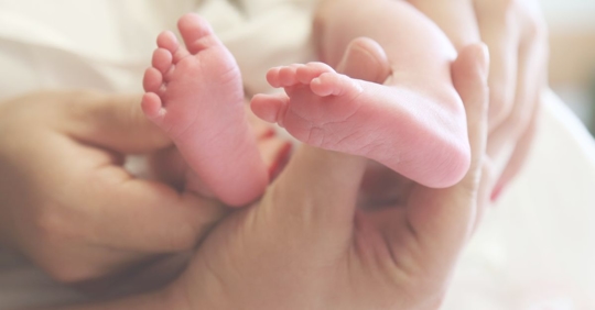 a mother hold baby feet