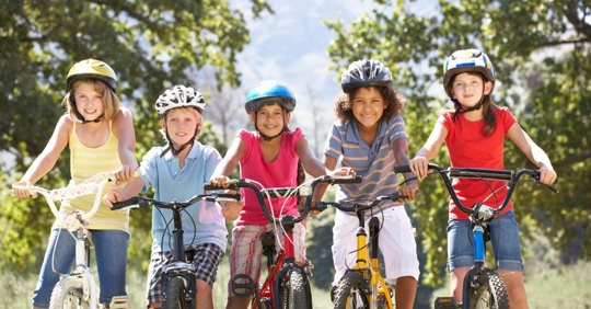 group of multiracial children riding bikes and wearing helmets