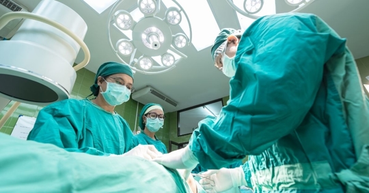 group of doctors standing over a patient during a surgery