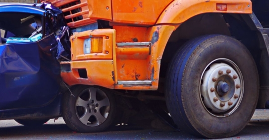 close up of a car crashed into a semi-truck bumper