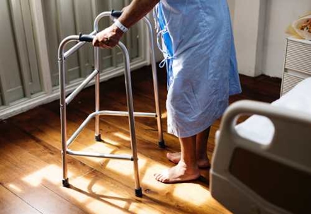 Elderly person in hospital robe with walker
