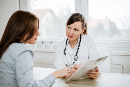 Woman looking at papers with doctor