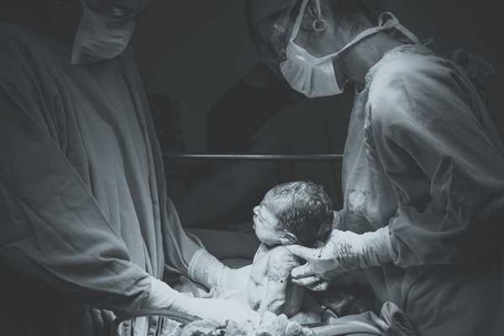 Doctors holding newborn baby